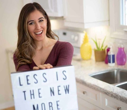 Is it Time to Start Living a Minimalist Life? Melissa holding a sign: Less is the New More