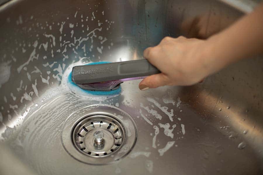 Cleaning the sink with the scotch-brite dish wand