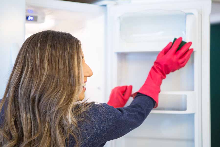 Melissa wearing dishwashing gloves cleaning the fridge