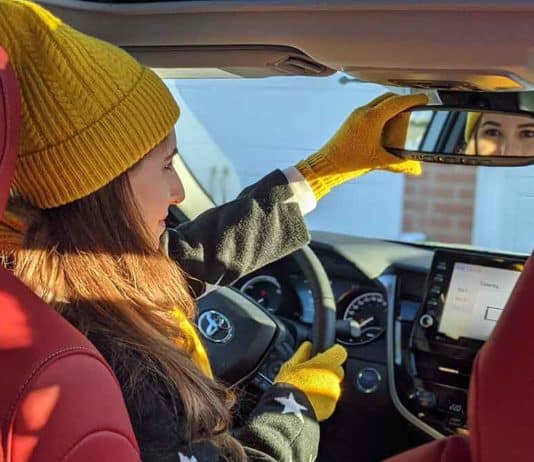 Car Interior Cleaning: The Ultimate Guide Melissa in her car looking into the mirror