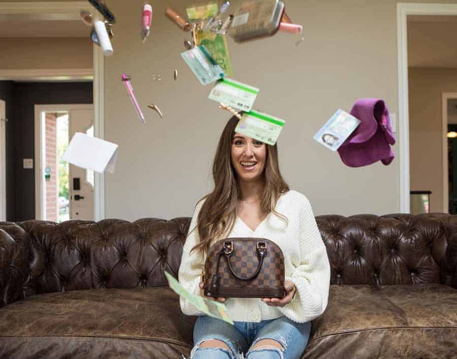 Melissa holding a leather purse with objects flying in the air