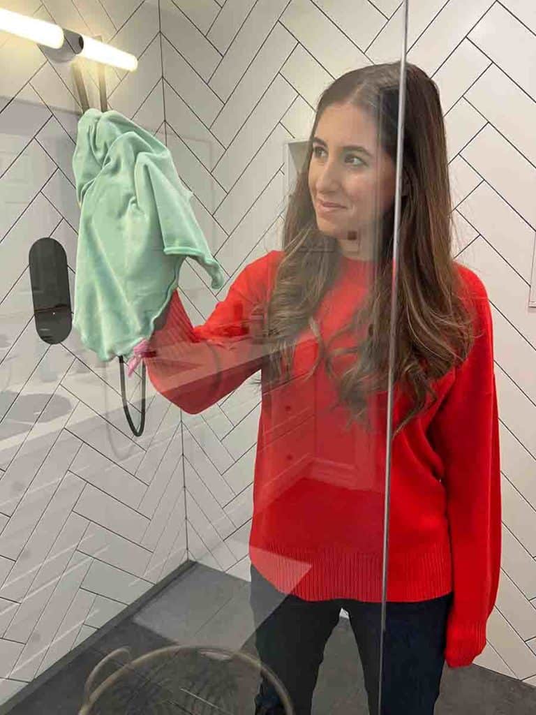 Melissa Maker wiping glass shower door with microfiber cloth
