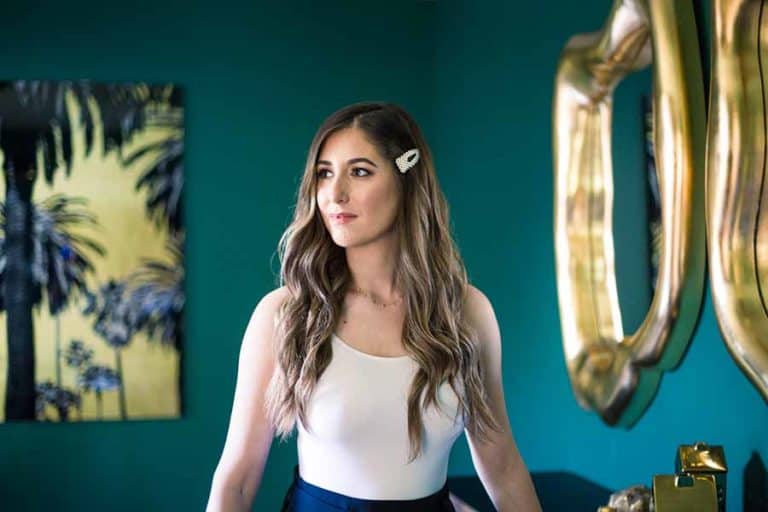 Melissa in white tank top standing in front of green wall
