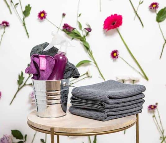 The Best Spring Cleaning Checklist cleaning supplies against a wall with flowers