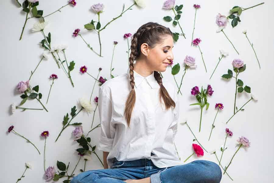 Melissa sitting against a wall of flowers