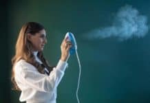 How to Steam Clothes: Wrinkled Clothes Begone! Melissa Maker holding a clothes steamer shooting steam