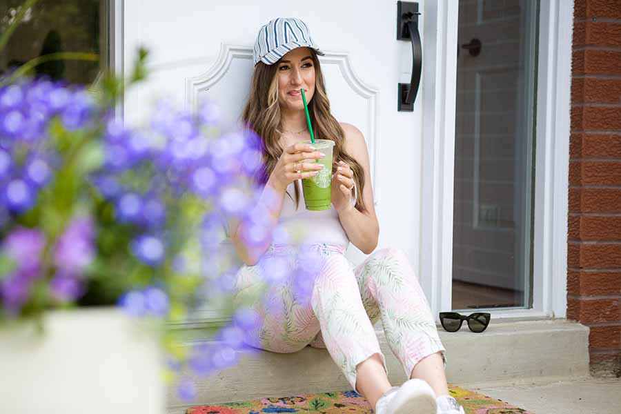 Melissa wearing a baseball cap and drinking a smoothie